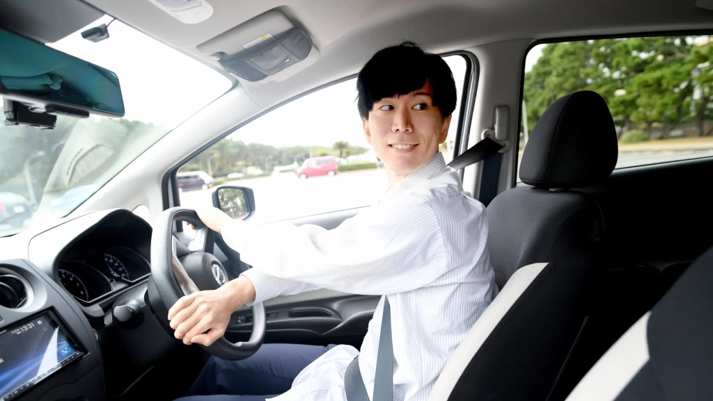 車をバックで駐車する男性の画像。